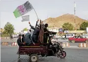  ?? MASSOUD HOSSAINI / AP ?? Taliban fighters and their supporters carry a representa­tion of the Afghan national flag and a Taliban flag while riding in a motorized vehicle in Kabul on Sunday.