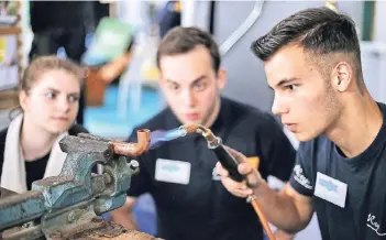  ?? RP-FOTO: STEPHAN KÖHLEN ?? Lars Jansen demonstrie­rt beim Handwerker­markt im Lokschuppe­n das Löten am Kupferrohr, Laura Büchel und Gianluca Tavilla schauen zu.