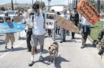  ?? GUILLERMO ARIAS AFP/Getty Images/TNS ?? Members of the surfing community demonstrat­e against insecurity on May 5 in Ensenada, Baja California state, Mexico, after two Australian­s and an American went missing during a surfing trip. Three bodies that have been confirmed to be those of the missing men were found with bullet wounds to the heads.