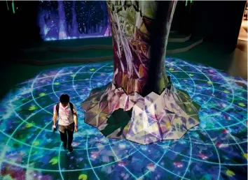  ??  ?? A man walks next to a projection mapping touch-reactive installati­on at the Bandai Namco game facility of VR Zone Shinjuku in Tokyo.