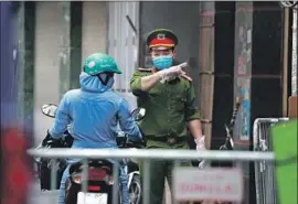  ?? Hau Dinh Associated Press ?? IN VIETNAM, where an outbreak was reported in the tourist hub of Da Nang, a police officer in Hanoi speaks to a woman near an area with a COVID-19 case.