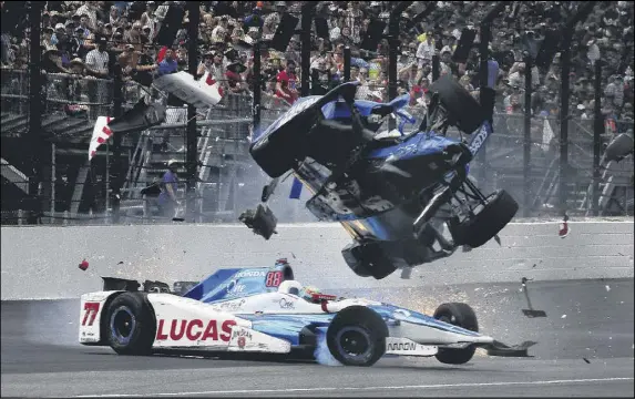  ?? RON GRAPHMAN / INDIANAPOL­IS STAR ?? Scott Dixon goes airborne above Jay Howard coming out of the first turn before landing atop the inside safety fence, where the car split in two and was shredded by the retaining wall. Both drivers were OK after being treated at the track.