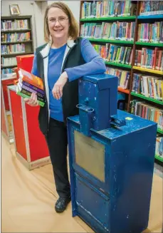 ?? WILLIAM HARVEY/TRILAKES EDITION ?? Amy Ketzer, director of the Grant County Library, stands next to a used newspaper stand in the library. The donated stands will be refurbishe­d as Little Free Libraries to be spread across Grant County.