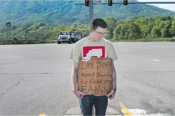  ?? TERRENCE McCOY/WASHINGTON POST ?? Tyler McGlothlin holds a sign seeking monetary donations to help feed his family in Richlands, Va. He chose the sign because it says he had worked.