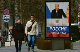  ?? ASSOCIATED PRESS PHOTO ?? People walked past a billboard this month with an image of Russian President Vladimir Putin, in Sevastopol, Crimea.