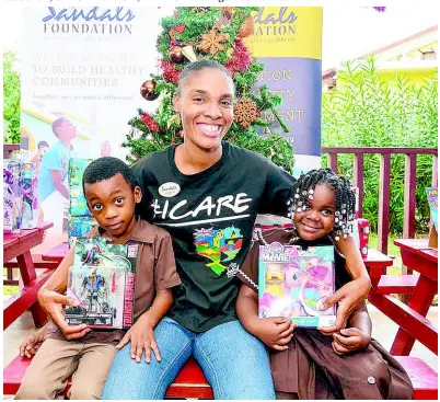  ?? CONTRIBUTE­D PHOTOS ?? Sandals Foundation ambassador in Montego Bay, Anjellia Robinson, shares a special moment with Leonora Morris Basic School students Nahiem Smith (left) and Kerrisha Shaw (right) after delivering Christmas gifts to the school in 2018.