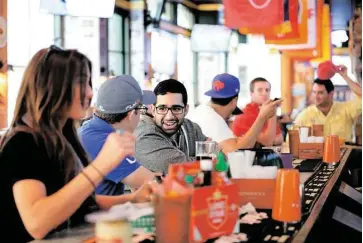  ?? Jon Shapley / Houston Chronicle ?? Akbar Dosan, center, chats with Josh Wardell at a downtown bar. Both work in investment banking.