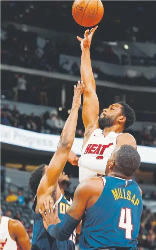  ?? David Zalubowski, The Associated Press ?? Miami Heat guard Dwyane Wade goes up for a basket between Nuggets guard Malik Beasley, back, and forward Paul Millsap on Monday night. It was the final game at the Pepsi Center for Wade, who is retiring after this season.