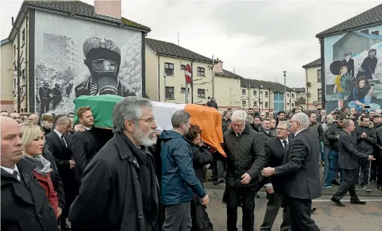  ?? PHOTOS: REUTERS ?? Sinn Feinn President Gerry Adams, foreground, walks alongside the coffin of Martin McGuinness as it is carried through crowded streets during his funeral in Londonderr­y, Northern Ireland.