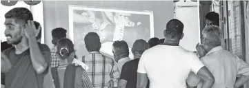  ?? — AFP photo ?? Relatives of bomb blast victims watch a large screen with images of bodies with identifica­tion tags attached being projected at a morgue in Colombo as they hope to identify loved ones missing or killed in the Easter Sunday bomb attacks.