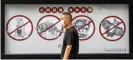  ?? Photograph: Alex Plavevski/EPA ?? A man walks past a poster warning people in Guangdong province, China, that consuming wildlife is illegal.