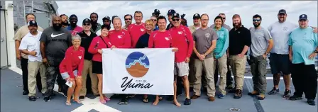  ??  ?? THE RESCUED CIVILIANS, ALONG WITH MEMBERS OF THE USNS YUMA, pose with the City of Yuma flag. The ship is named after the city.