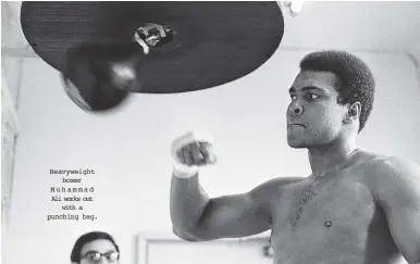  ??  ?? Heavyweigh­t boxer Muhammad Ali works out with a punching bag.