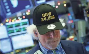  ?? DREW ANGERER/GETTY IMAGES ?? A trader wears a Dow 24,000 hat at the New York Stock Exchange on Nov. 30, the day the Dow closed above that mark for the first time.