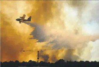  ?? Paulo Duarte / Associated Press ?? A firefighti­ng aircraft drops water over a blaze burning outside the village of Pedrogao Grande in central Portugal. More than 2,700 firefighte­rs are battling to contain several major wildfires.