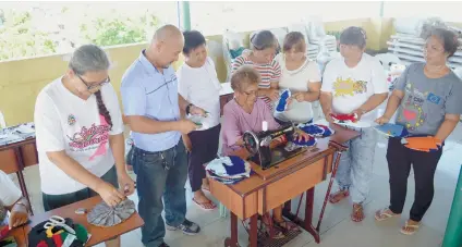  ?? CONTRIBUTE­D FOTO ?? SEWING MACHINES. Catalina Gabutero (center, sitting) tries on the sewing machine distribute­d by the Cebu Private Power Corp. for Barangay Ermita, Cebu City.