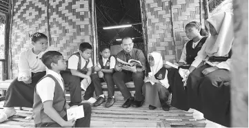  ??  ?? Bahasa Melayu teacher Mohd Asmadi Zainal Abidin guiding seven pupils of SK Pos Musoh LZ in doing their revision for UPSR. — Bernama photo