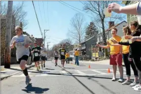  ??  ?? Volunteers stand with water for runners in the 10K race at the intersecti­on of Wurts and Abeel streets as runners turned to go onto the Rondout Creek Bridge.