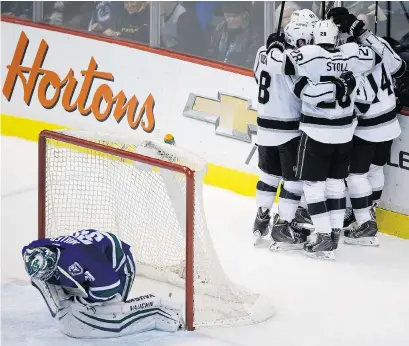  ?? DARRYL DYCK/THE CANADIAN PRESS ?? Vancouver Canucks goaltender Ryan Miller leans over in front of his net as Los Angeles Kings teammates Drew Doughty, Alec Martinez, Dustin Brown, Jarret Stoll and Justin Williams celebrate Williams’ goal on Thursday night at Rogers Arena.