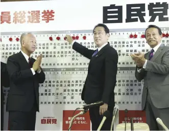  ?? Yomiuri Shimbun file photo ?? Prime Minister Fumio Kishida, second from right, poses as he places a rosette symbolizin­g victory on a board bearing the names of House of Representa­tives election candidates in Tokyo on Oct. 31 last year.
