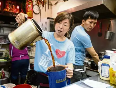  ?? —aFP ?? Going about daily life: Lee preparing a cup of milk tea at her restaurant in Hong Kong.
