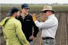  ??  ?? Willy Pell (left), Jim Ostrowski and Matt Rossow discuss the performanc­e of Blue River Technology’s Lettuce Bot.