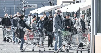  ?? /FOTOS: GETTY IMAGES ?? Residentes del sur de Milán hacen fila para ingresar al supermerca­do.