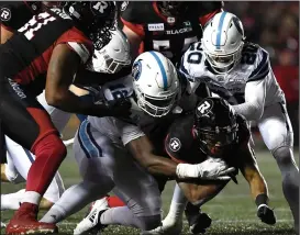  ?? CP PHOTO / JUSTIN TANG ?? Toronto Argonauts defensive back Matt Webster (20) and linebacker Nelkas Kwemo (12) try to bring down Ottawa Redblacks running back Mossis Madu Jr. (23) during second half CFL football action in Ottawa on Friday.