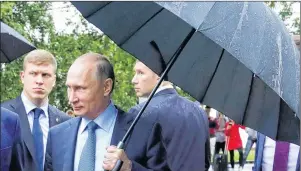  ?? AP PHOTO ?? Russian President Vladimir Putin holds an umbrella as he looks at an outdoor fitness equipment installed on the Onezhskaya Embankment in Petrozavod­sk, Russia, Wednesday.