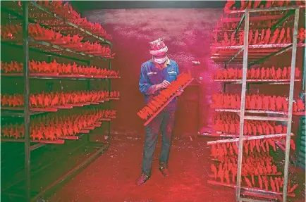  ?? PHOTO: REUTERS ?? A man wearing a Christmas hat works at a factory producing Christmas decoration­s in Yiwu, Zhejiang province.