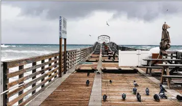  ?? MELANIE BELL / THE PALM BEACH POST ?? The Lake Worth Pier was closed on Tuesday because of high surf. Some deck parts were taken off to allow waves to break through. Parts of Palm Beach County could see wind chills in the 20s in the coming days.