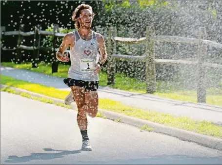  ?? DANA JENSEN/THE DAY ?? Everett Hackett of West Hartford runs through a sprinkler placed by a resident in Waterford along the route of the Saturday’s Ocean Beach/ John & Jessie Kelley Half Marathon. Hackett cruised to an easy victory. Visit www.theday.com to view a photo gallery.