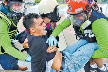  ?? RONALDO SCHEIDT/AFP ?? Un manifestan­te opositor es ayudado por médicos durante los choques en Caracas.