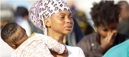  ?? Photo: AFP ?? A woman holding a baby cries as illegal migrants of different African nationalit­ies arrive at a naval base in Tripoli, Libya yesterday, after they were rescued from inflatable boat off the coast of Al-Zawiyah