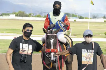  ?? ?? Trainer Ian Parsard (left) leads in his outstandin­g filly She’s A Wonder. The jockey is Dane Dawkins and the groom at right is Kenneth Kaple.