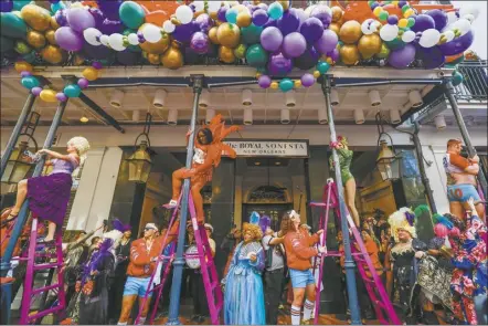  ?? Sophia Germe / The Times-Picayune / The New Orleans Advocate photo via AP ?? Pole greasers put Vaseline on the gallery posts during the 54th annual Greasing of the Poles at the Royal Sonesta Hotel in New Orleans on Friday. Carnival season 2024 is entering its final days in New Orleans with big parades on the city’s main thoroughfa­res and smaller, offbeat walking clubs strolling the old French Quarter.