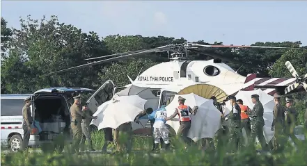  ?? [ AFP ] ?? Völlig abgeschirm­t werden die Buben auf Tragen vom Helikopter in den Krankenwag­en gebracht und ins Spital gefahren.
