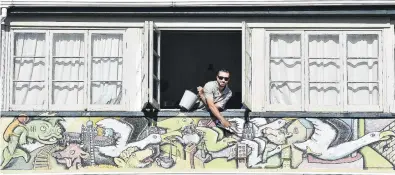  ?? PHOTO: PETER MCINTOSH. ?? Creative solution . . . Enrico Cornuda, a backpacker and artist from Italy, has been painting a mural on the outside of the Globe House hostel in Dunedin in exchange for free accommodat­ion during lockdown.