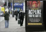  ?? ASSOCIATED PRESS FILE PHOTO ?? Pedestrian­s pass a sign on a bus stop in West Ealing in London.