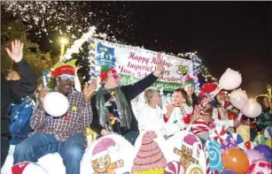  ??  ?? A group of people shout in excitement while riding on the Imperial Valley Home School Academy float during the 15th annual Parade of Lights on Friday night in Imperial. VINCENT OSUNA PHOTO