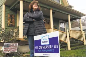  ?? Gillian Flaccus / Associated Press ?? Kelly Burke stands outside her Portland home next to a sign supporting Oregon’s Measure 101. The tax would help fund state health care costs.