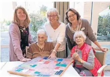  ?? FOTO: DANIELA GIESS ?? Die Künstlerin Elke Wergers (2.v.l., stehend) zeigt bis Mitte Mai ihre Werke im Johanniter­stift. Einrichtun­gsleiterin Astrid Hadick (r.) und Monique Drescher vom Sozialen Dienst (l.) freuen sich.