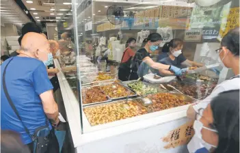  ?? — AFP photos ?? Customers queuing for low-priced two-dish mealboxes at Kitty Chan’s restaurant.