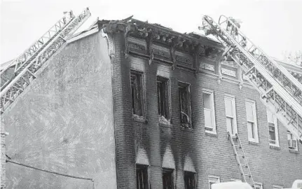  ?? KIM HAIRSTON/BALTIMORE SUN ?? Fire equipment surrounds the charred rowhouse in East Baltimore after the Saturday-morning fire. Officials suspect that the fire was caused by Molotov cocktails. A shooting Thursday in the same location could be connected to the blaze, police said.