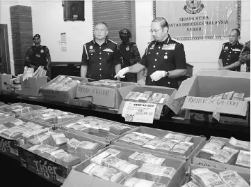  ??  ?? Mustafar (centre) shows the RM13.5 million cash found by immigratio­n officers during the raid at a hotel spa and an apartment.