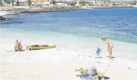  ?? CARLOS DE SAÁ / EFE ?? Un pequeño grupo de turistas en la localidad canaria de Corralejo, en Fuertevent­ura, esta misma semana.