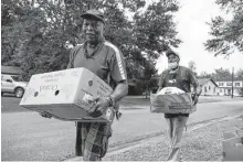  ?? Gustavo Huerta / Staff photograph­er ?? Henry Caylen, left, and Sherman Benoit carry boxes of food out to vehicles during a food pantry pickup event in July at Pilgrim Rest Missionary Baptist Church.