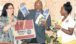 ??  ?? “It’s two” exclaims a gleeful Dr Robert Leger, Governor of Rotary Internatio­nal’s District 7020 as he discovers two packets of Blue Mountain Coffee in a gift bag presented to him by Melissa Stoddart (right) of the Rotaract Club of Negril. At left is Dr Leger’s wife, Rosa.