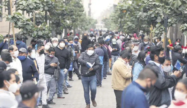  ??  ?? People wait in line for some businesses to reopen in downtown Lima, Peru, July 1, 2020.