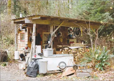  ?? PHOTOS BY LAUREN FIELD / THE NEW YORK TIMES ?? Emmy Madav, left, weaves outside her cabin on the Olympic Peninsula, Wash. Dense forest obfuscates the dwellings of a scattered community of people who live off the grid — tiny houses, trailers, a landlocked houseboat — often accessible only by dirt...